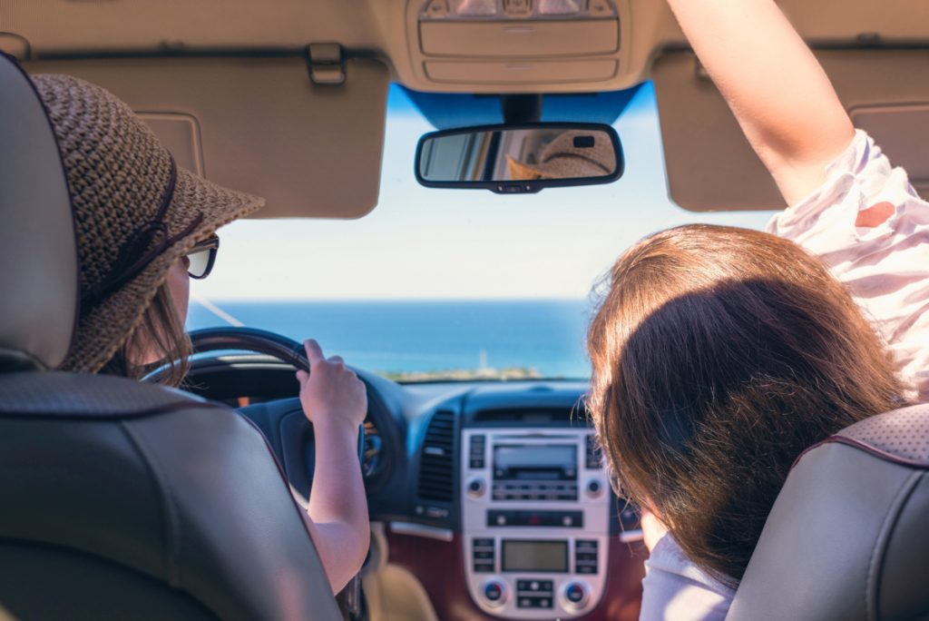 Two girls traveling by car near the water.